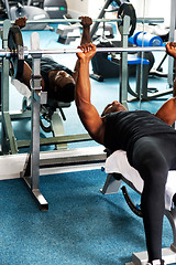 Image showing Young sporty fit guy doing barbell bench press