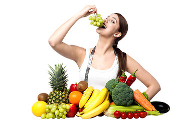 Image showing Young smiling girl eating grapes, looking at camera