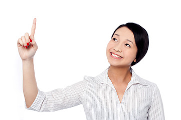 Image showing Smiling pretty girl looking and pointing upwards