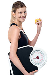 Image showing Fit girl holding fruit and weighing scale