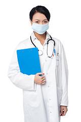 Image showing Surgeon holding clipboard. Face covered with surgical mask