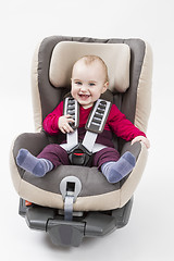 Image showing happy child in booster seat for a car in light background