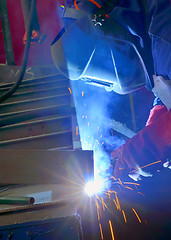 Image showing welder with protective mask welding metal and sparks