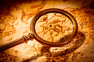 Image showing Vintage magnifying glass lies on an ancient world map