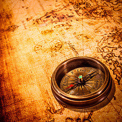 Image showing Vintage compass lies on an ancient world map.