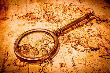 Image showing Vintage magnifying glass lies on an ancient world map