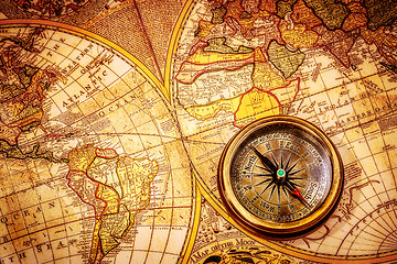 Image showing Vintage compass lies on an ancient world map.