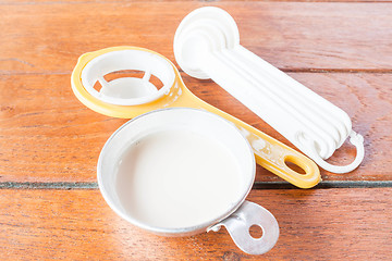 Image showing Beginning step of bakery preparation with milk, spoon and yolk s