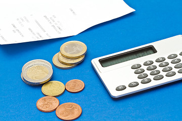 Image showing Several euro coins, bill and calculator on blue background