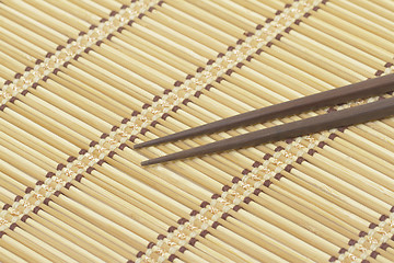 Image showing Dark wooden chopsticks on bamboo mat