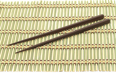 Image showing Dark wooden chopsticks on bamboo mat