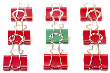 Image showing Green paper clip among red