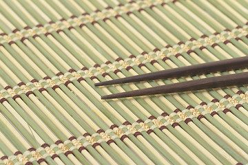 Image showing Dark wooden chopsticks on bamboo mat