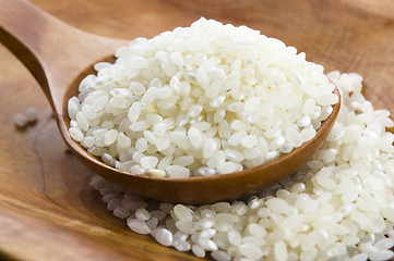 Image showing Rice in wooden spoon on kitchen table