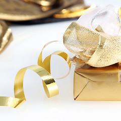 Image showing Pretty gold wrapped gift and twirled ribbon