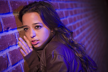 Image showing Frightened Pretty Young Woman Against Brick Wall at Night