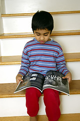 Image showing Kid reading a magazine