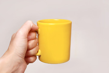 Image showing Hand holding yellow mug