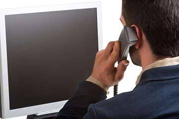 Image showing Casual Businessman Talking over the Phone and Looking at a Compu