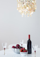 Image showing Red wine with fruits on a table, and beautiful chandelier