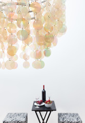 Image showing Bottle of red wine on a table, beautiful chandelier decorating a