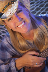 Image showing Beautiful Cowgirl Near Campfire Playing Her Ukulele