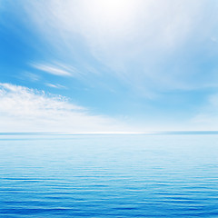 Image showing light waves on blue sea and cloudy sky with sun