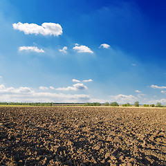 Image showing black ploughed field under deep blue sky with clouds