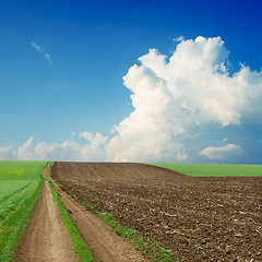 Image showing dirty road near green and black field under cloudy sky