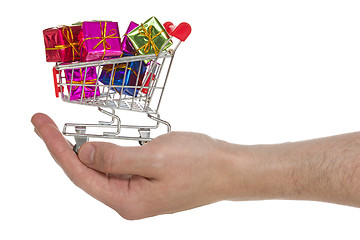 Image showing Hand with shopping cart full of colorful gifts