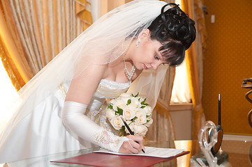 Image showing Pretty bride signing document