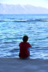 Image showing Small boy sitting on the coast of Adriatic sea