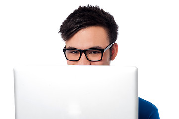 Image showing Mischievous boy hiding his face with laptop
