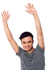 Image showing Cheerful young guy raising his arms