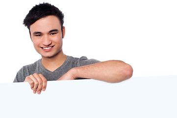 Image showing Casual young guy holding blank whiteboard