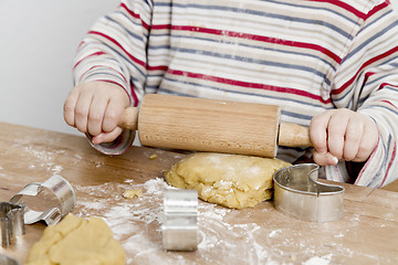 Image showing child rolling dough on wooden desk