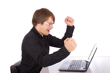 Image showing Business man raises arms in front of his laptop