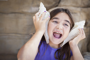 Image showing Young Girl Playing with Large Sea Shells Against Her Ears