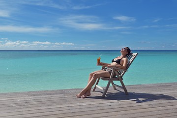 Image showing Beautiful young woman with a drink by the sea