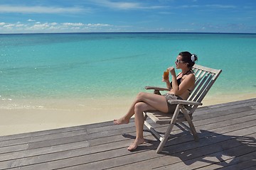 Image showing Beautiful young woman with a drink by the sea