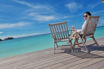 Image showing Beautiful young woman with a drink by the sea