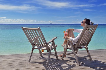 Image showing Beautiful young woman with a drink by the sea