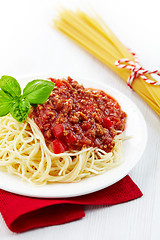 Image showing Portion of spaghetti bolognese with green basil leaf on white pl