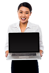 Image showing Smiling saleswoman presenting brand new laptop