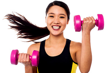 Image showing Happy fitness woman lifting dumbbells
