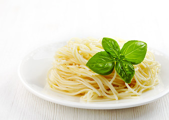 Image showing Pasta spaghetti and green basil leaf on white plate