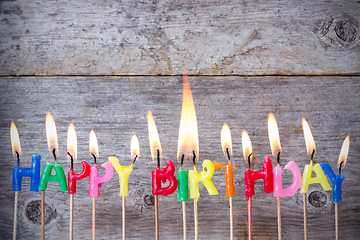 Image showing Birthday candles burn against wooden background