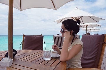 Image showing Beautiful young woman with a drink by the sea