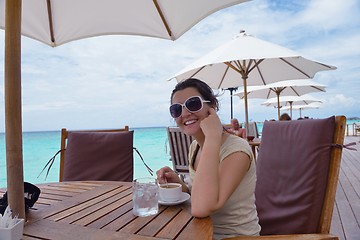 Image showing Beautiful young woman with a drink by the sea