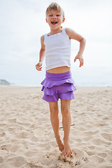 Image showing Young girl jumping in sand